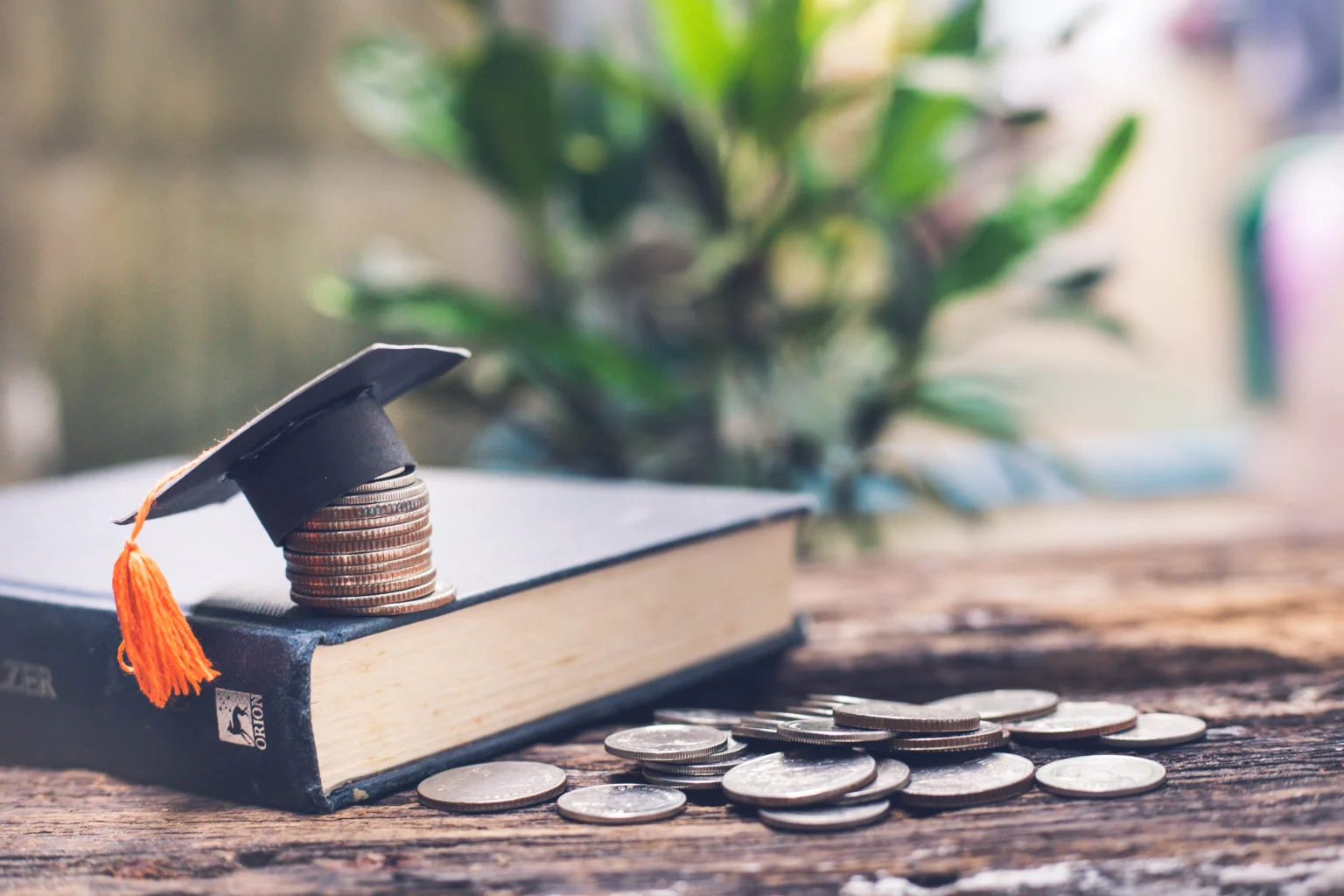 Coins with a graduation cap on top of a book