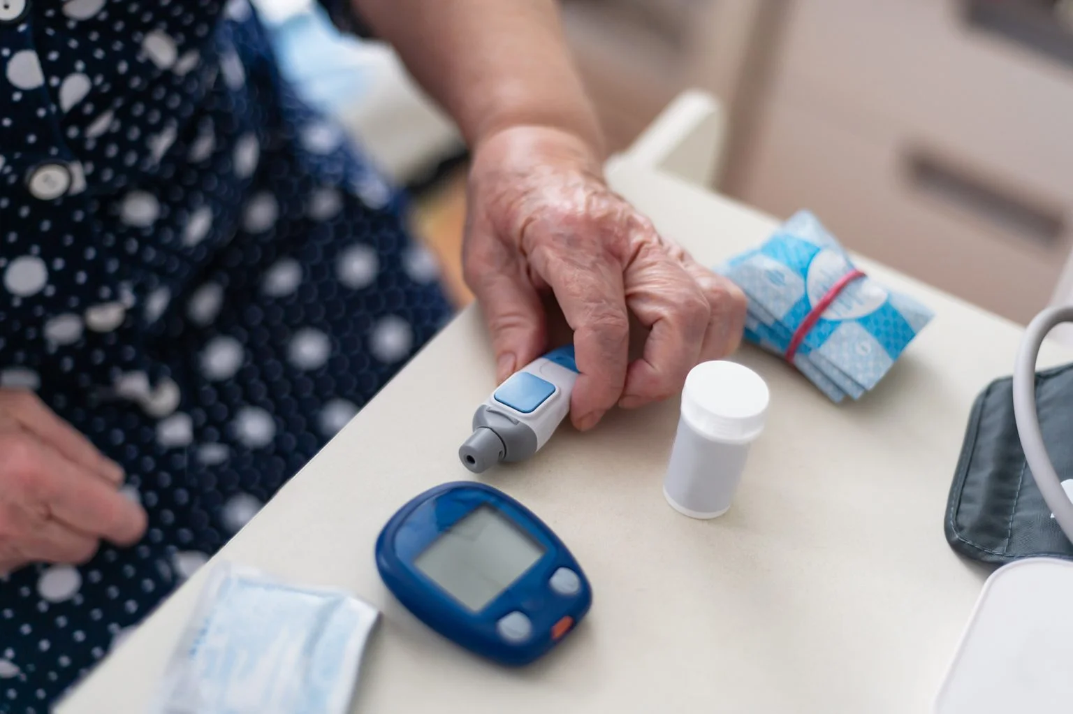 Senior hand using glucose monitors at a table