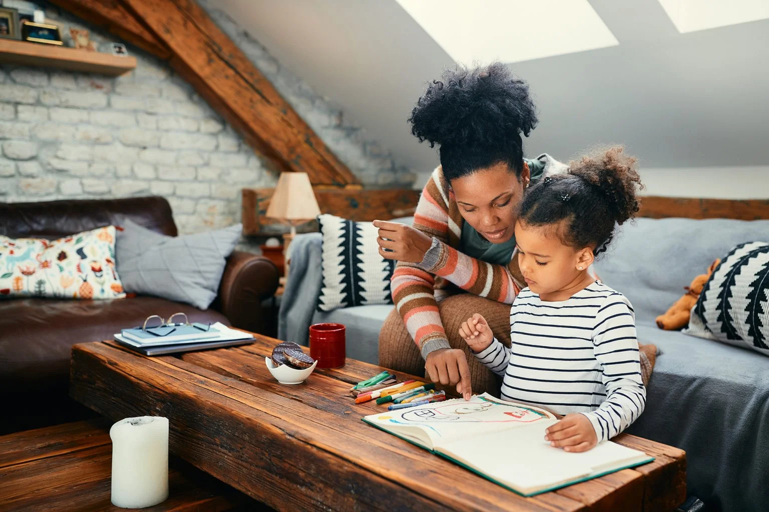 mother talks to her small daughter who is drawing on paper at home