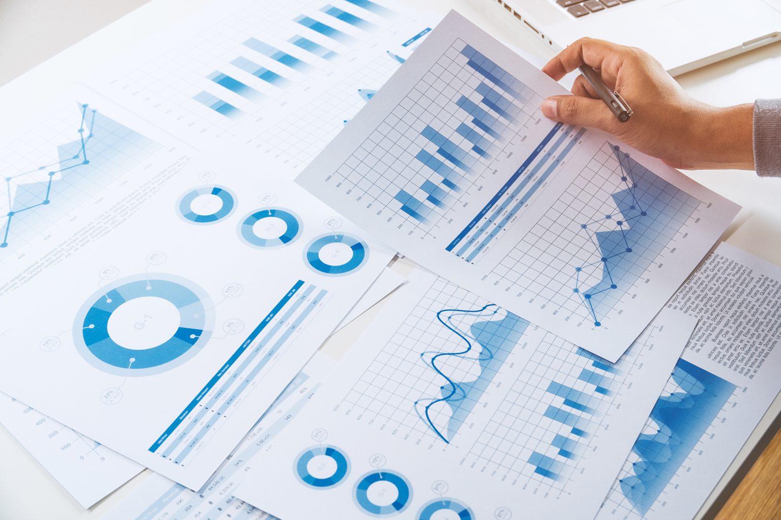 Hand holding paper with lots of financial charts and graphs