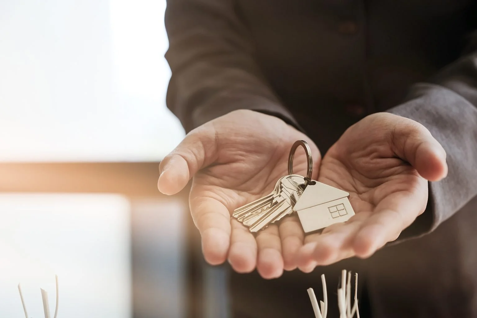 Hands cupped around keys with a keychain fo a house