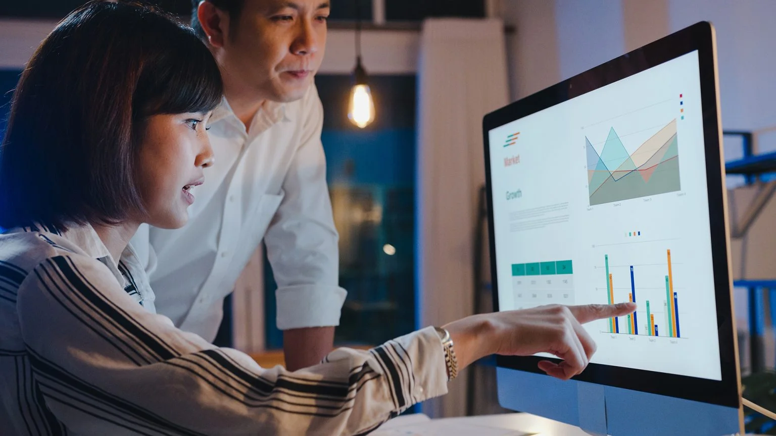 Two colleagues looking at data on a computer screen