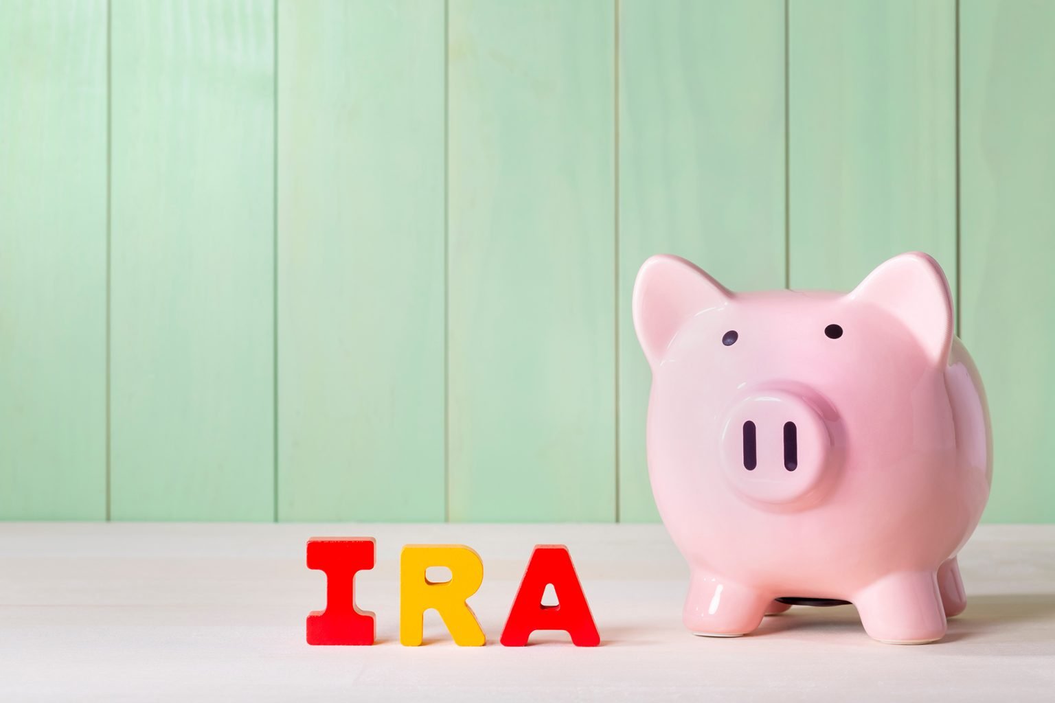 wood block letters that say IRA and piggy bank