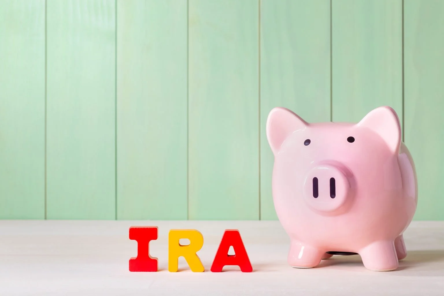 wood block letters that say IRA and piggy bank