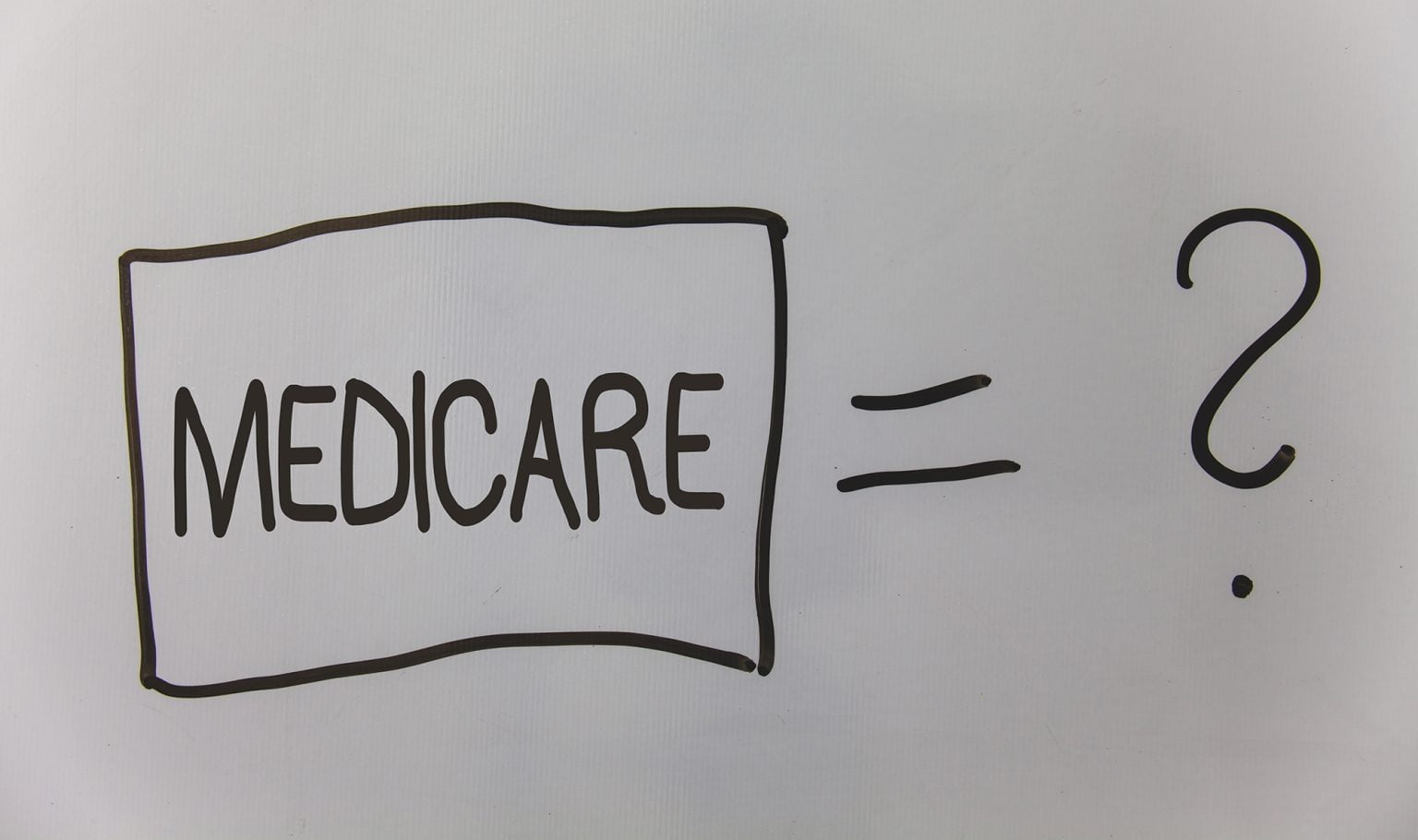 Whiteboard with the word Medicare written in a box next to an equal sign and a question mark
