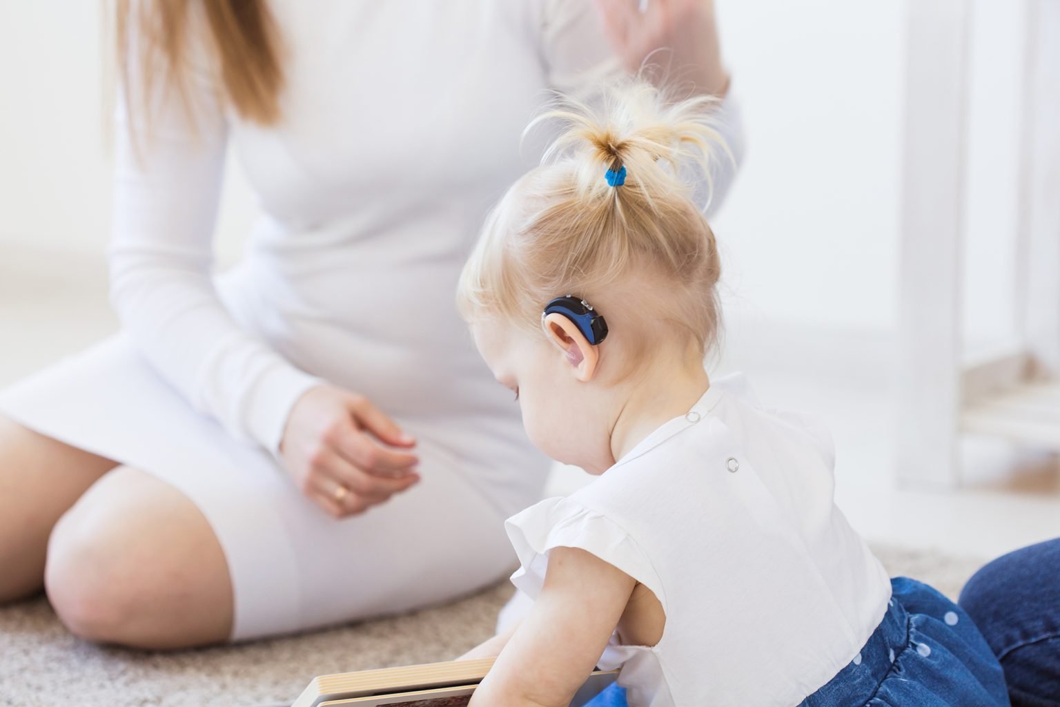 Toddler child wearing a hearing aid at home