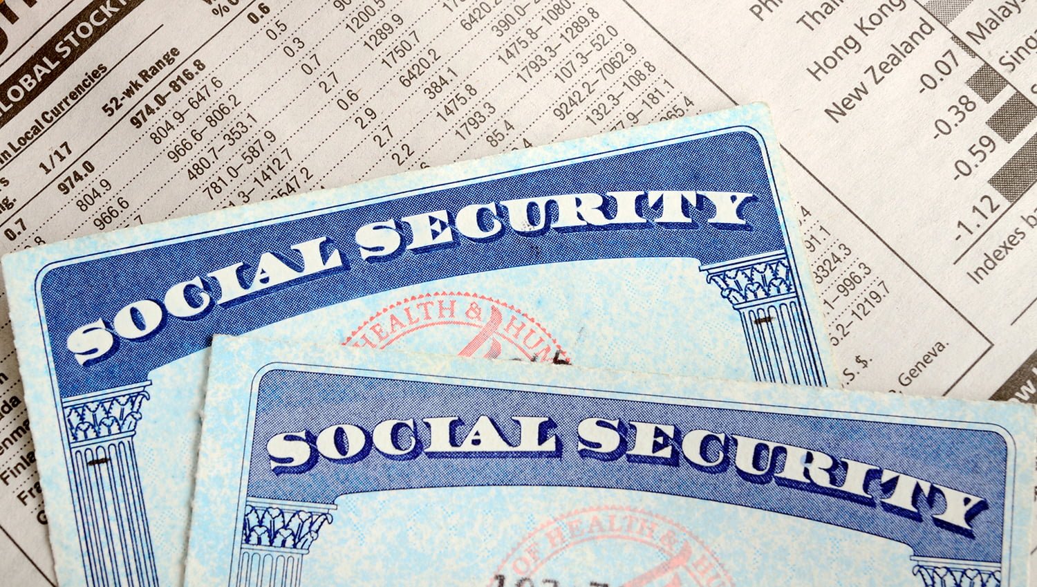 Social Security cards over a newspaper with stock market information