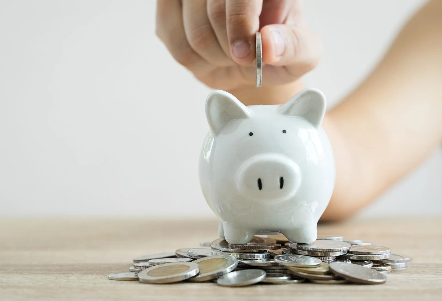 hand holding coin to put in piggy bank