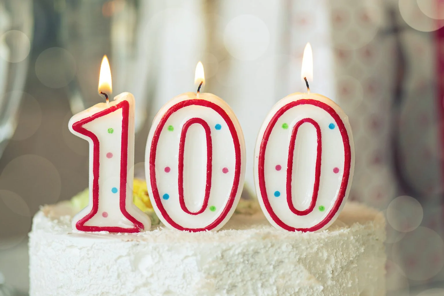 Birthday candle as number one hundred on top of sweet cake on the table