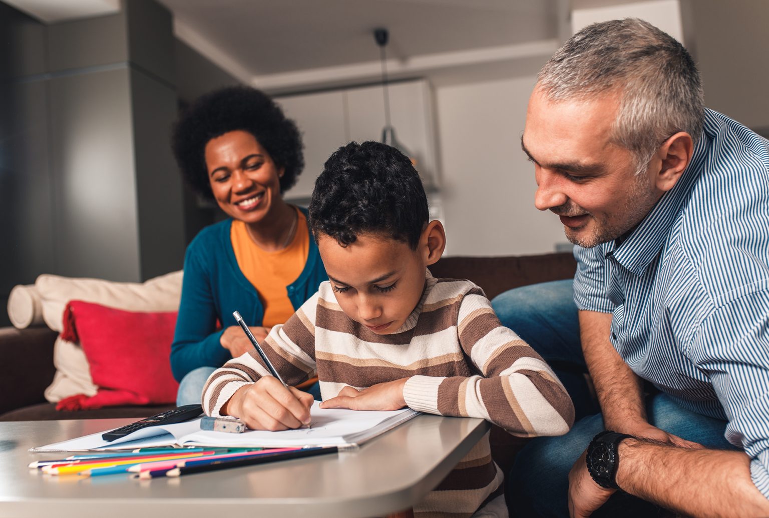 Parents helping their son with his homework at home in living room