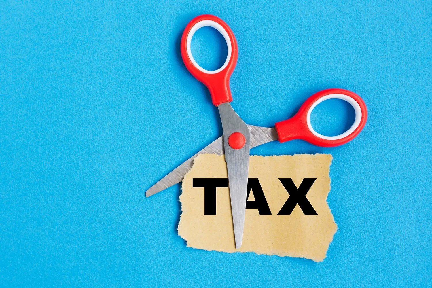 Tax word on paper cut by scissor, blue background
