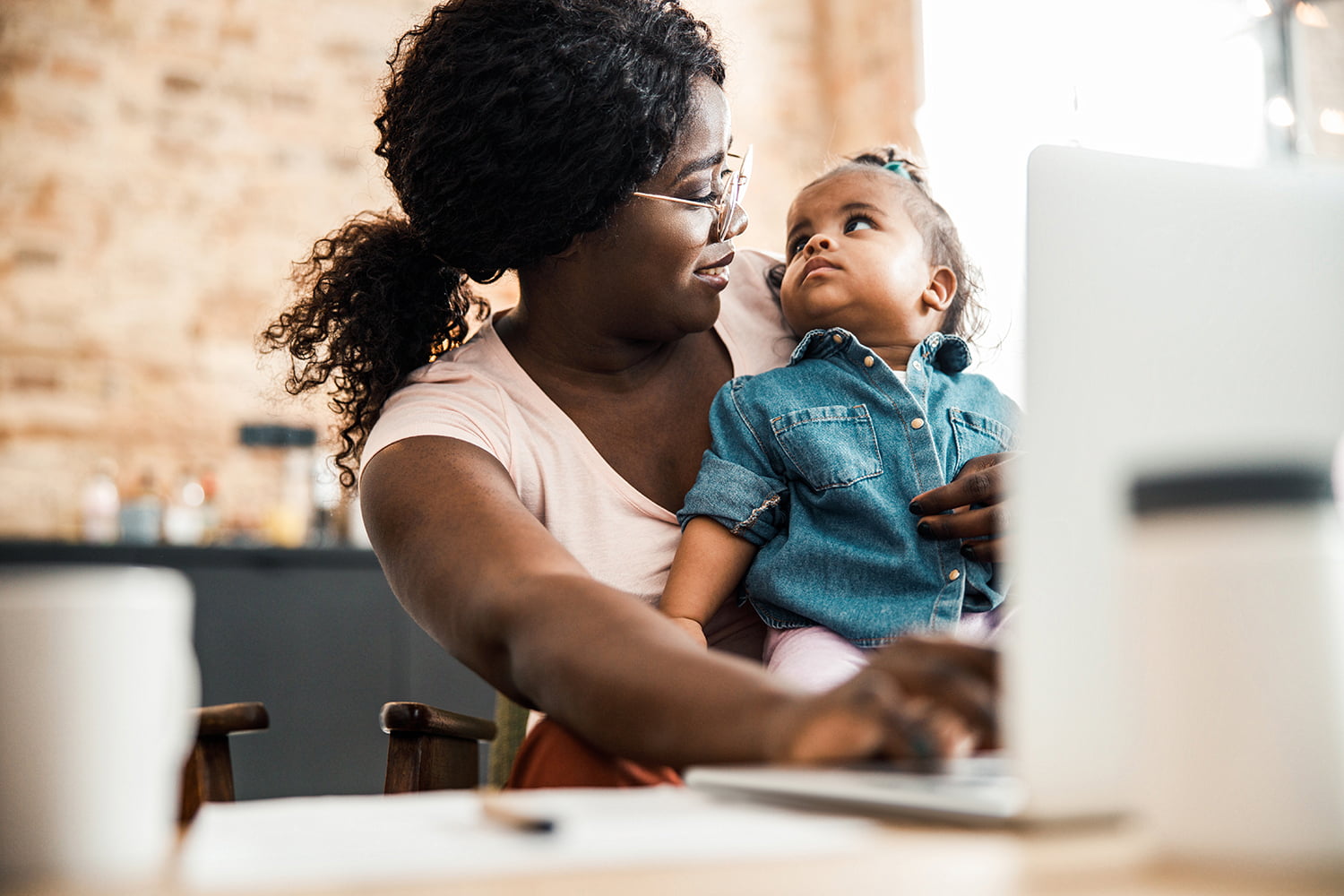 lady holding baby girl and using laptop