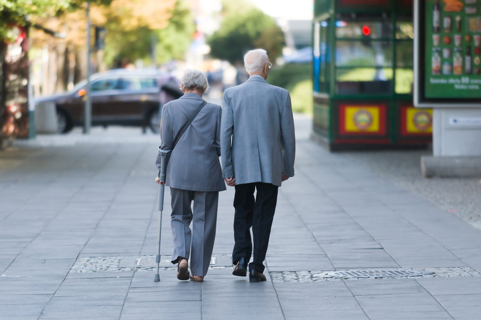 Rear view of an elderly couple walking along a sidewalk