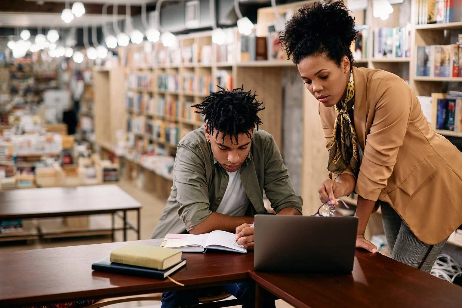 student e-learns with help of his teacher in library