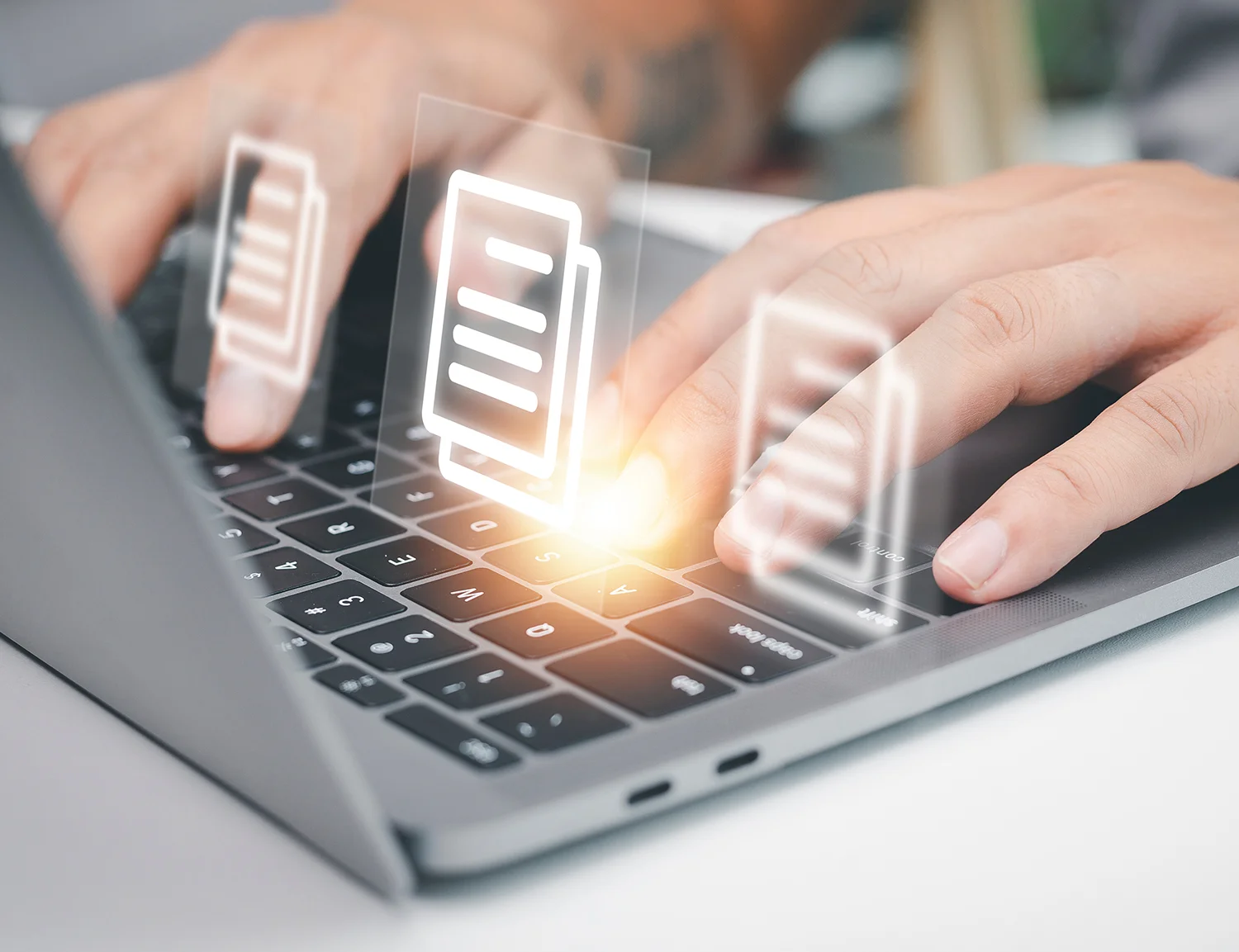 Fingers typing on a laptop with document icons floating above