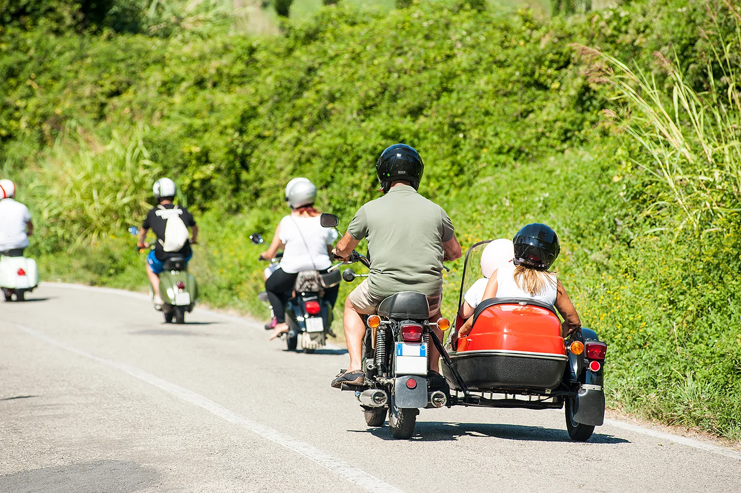 Rear view of a person on a motorcycle with a passenger in a sidecar