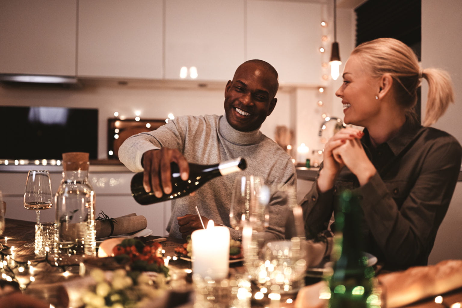 Smiling man pouring friends wine during a dinner party