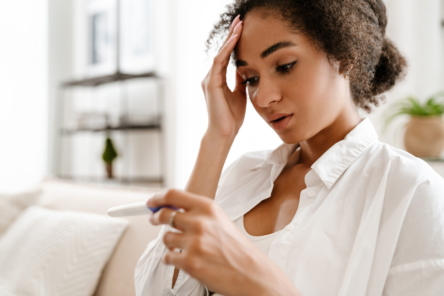 Young black woman being upset while holding pregnancy test at home