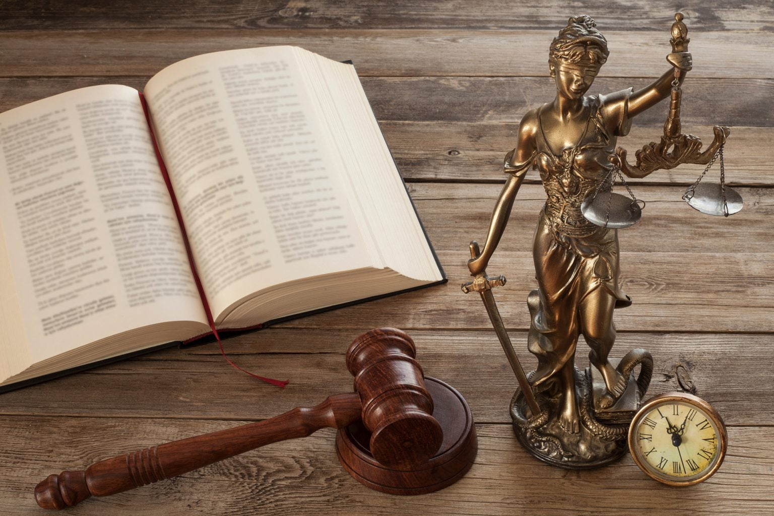 open book, gavel, and lady of justice statue on a wooden table