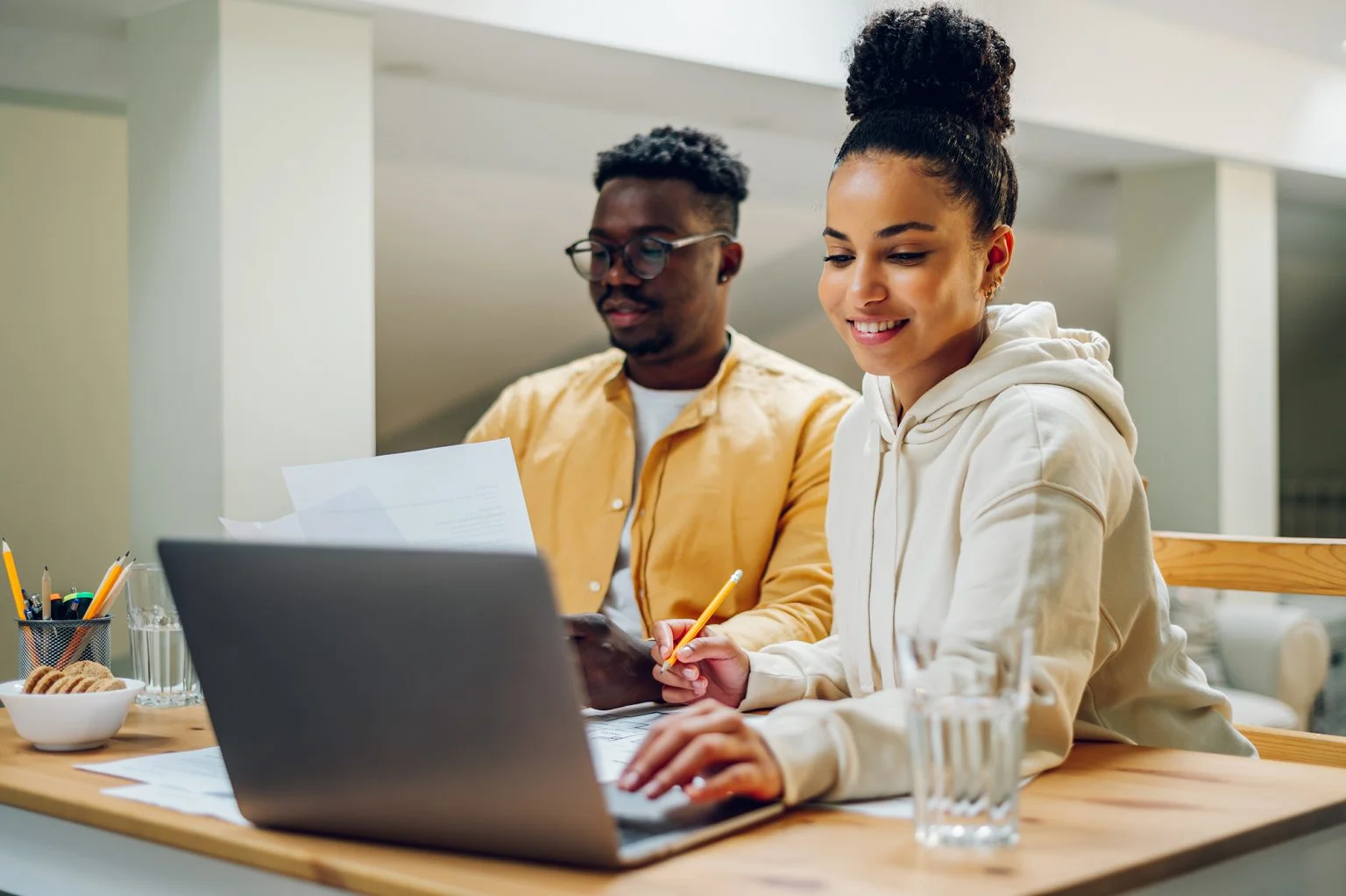 Diverse couple using laptop while sitting at the table at home