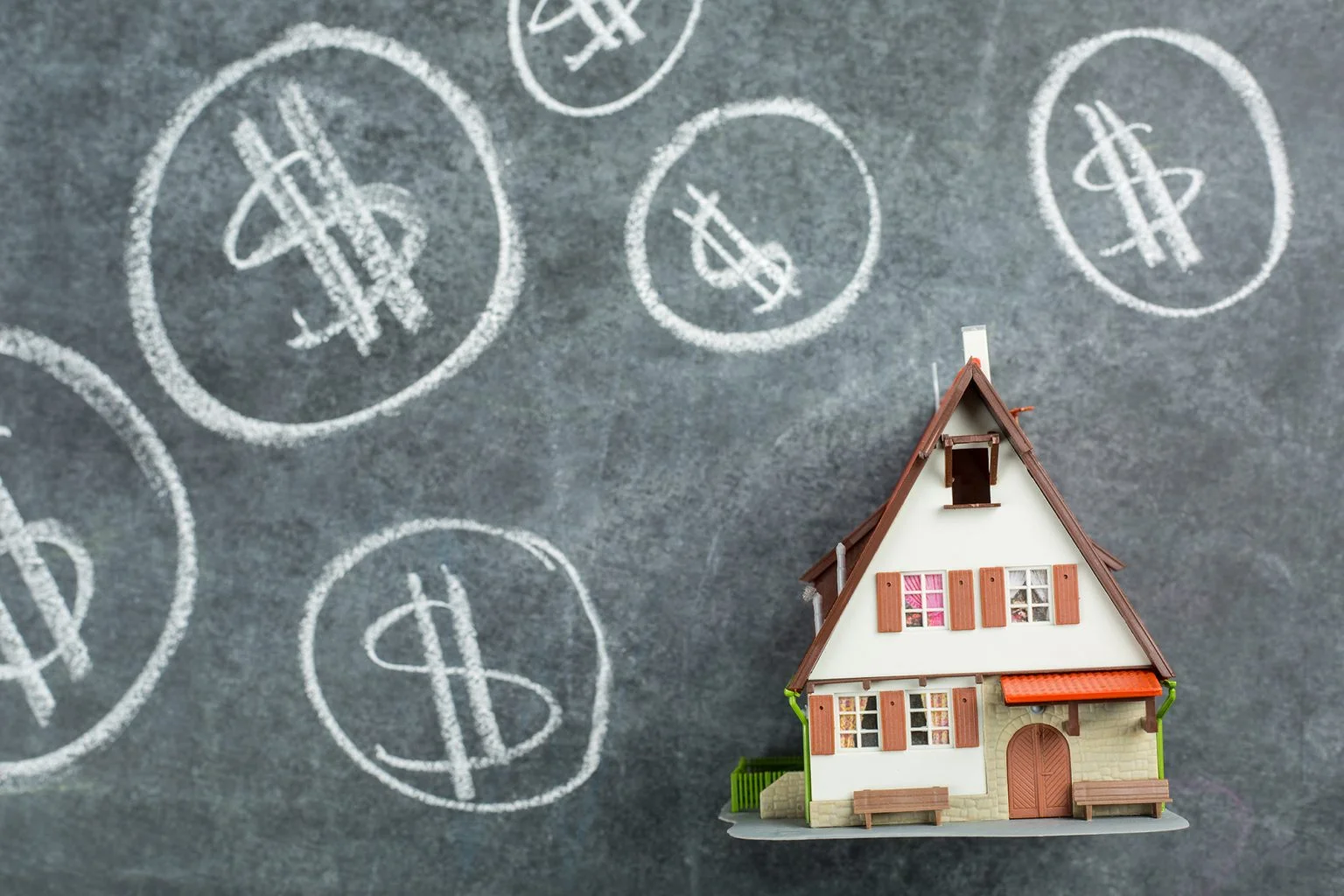 Model house on a chalkboard with dollar signs