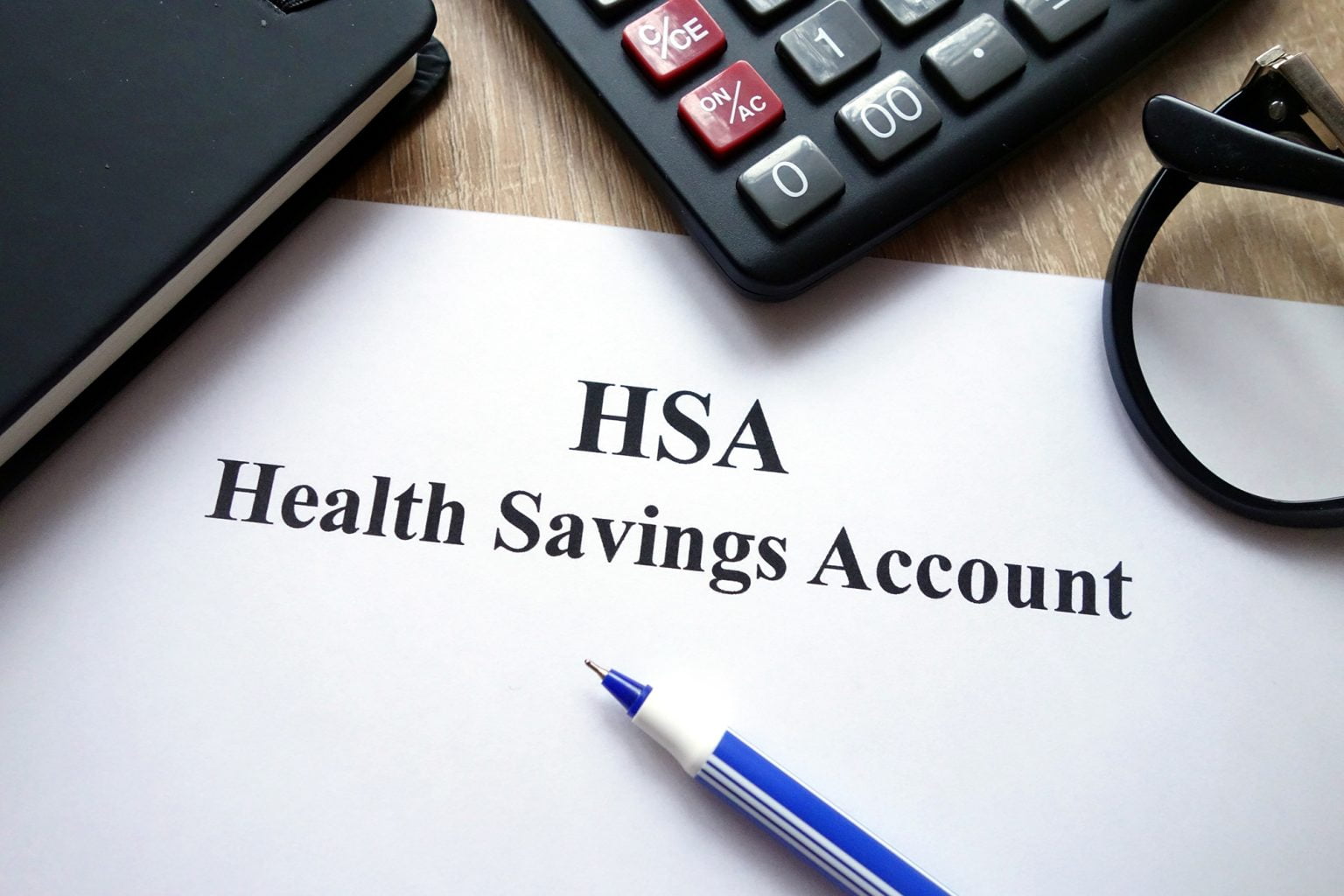 HSA health savings account document, calculator, pen and glasses on desk