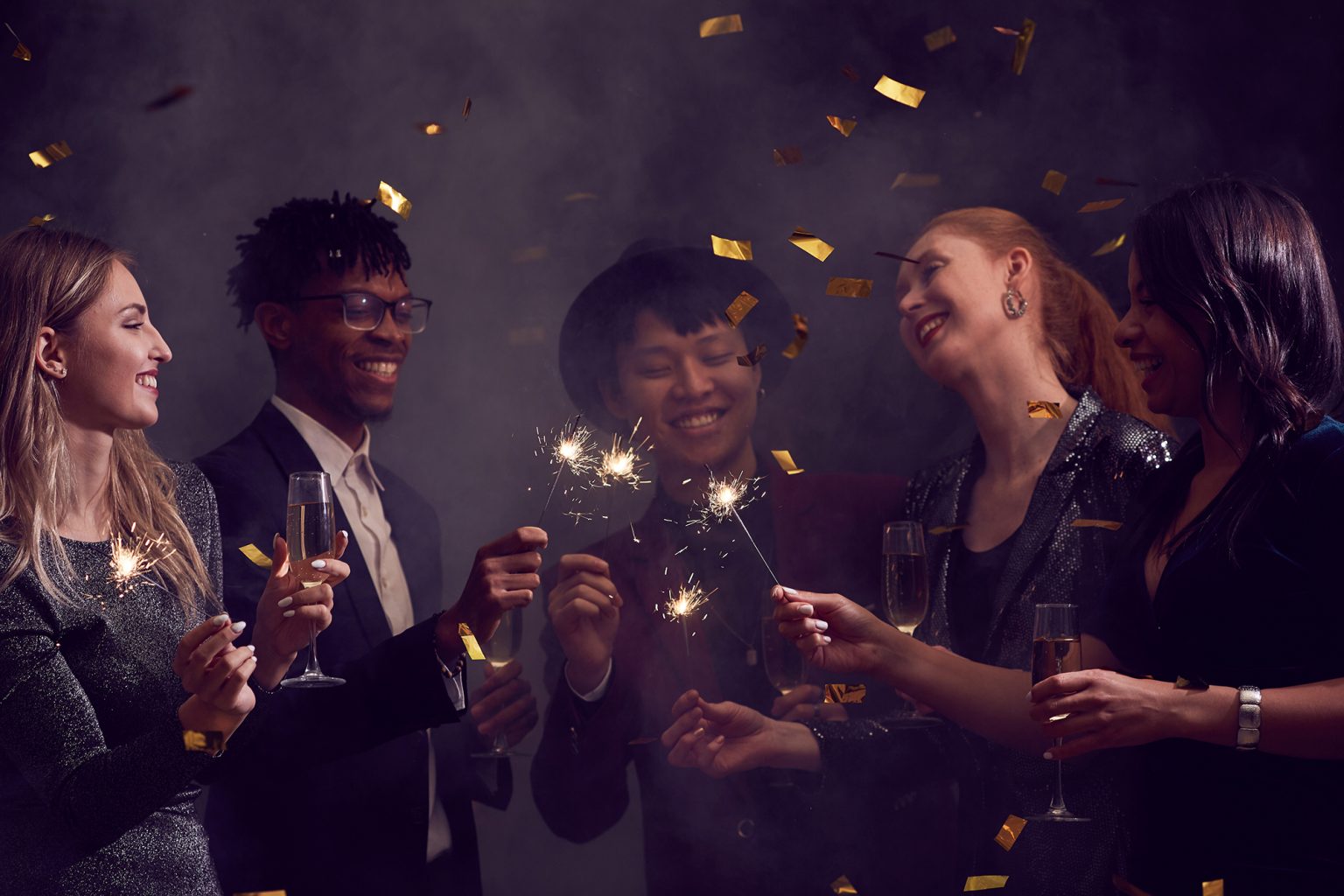 group of elegant people enjoying Christmas party in smoky night club with glitter falling overhead