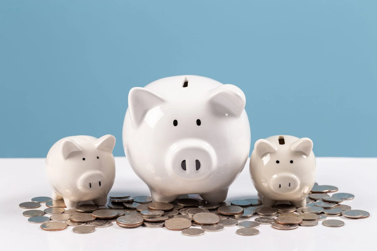 white ceramic piggy bank on stack coins on white wood table