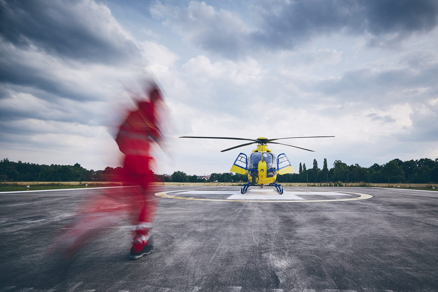 Person in red jumpsuit running towards an emergency helicopter