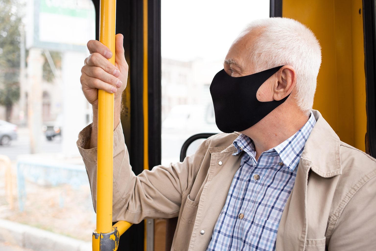 Senior man wearing medical face mask sitting in the bus transport