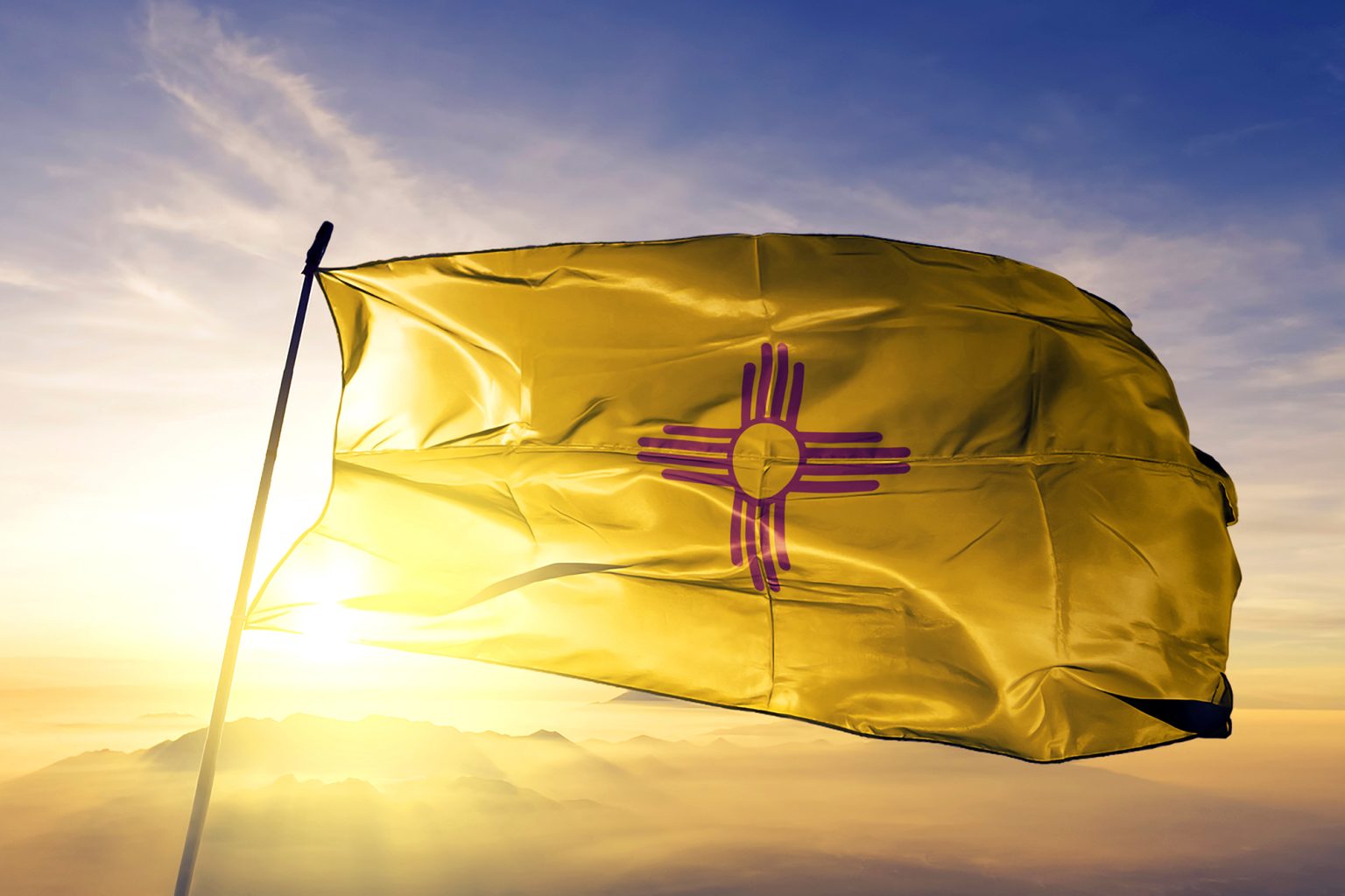 New Mexico state flag waving in front of sunrise