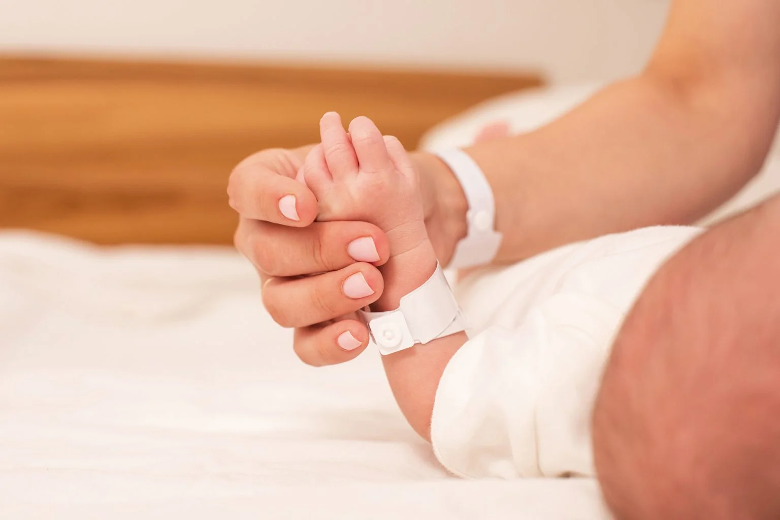 Close up of a newborn baby and mother holding hands with hospital bracelets