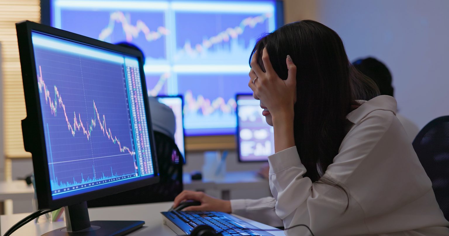 Stock market analyst in front of screen with a down market