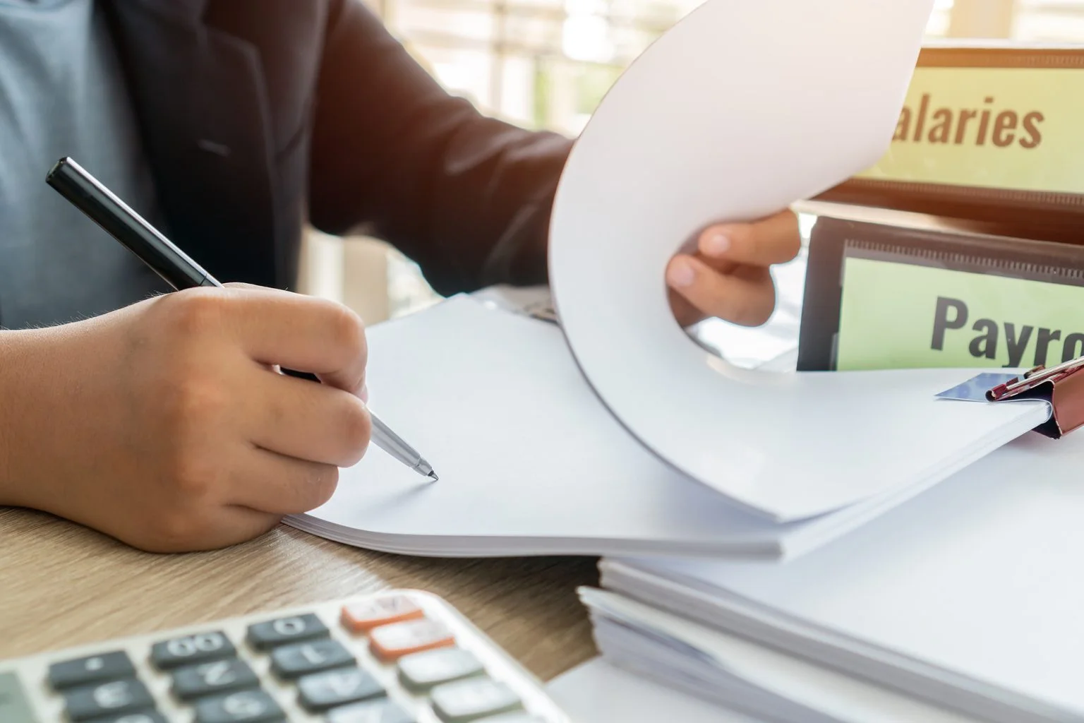 Businessman manager hands holding pen for reading, signing paperwork near payroll salary binder