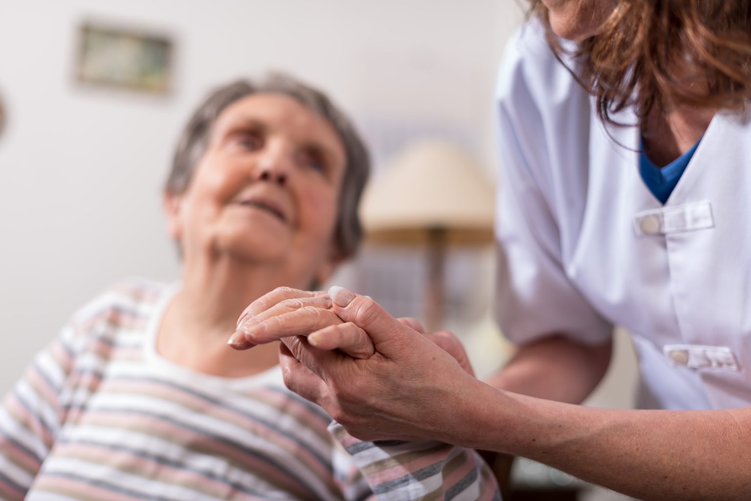 Nurse holding the hand of an elderly woman