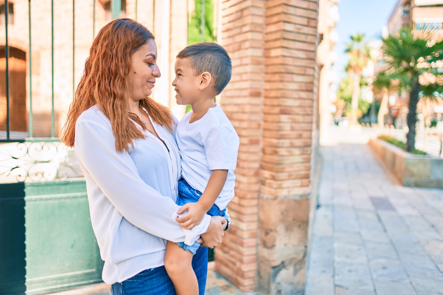 Adorable latin mother and son smiling on a city sidewalk