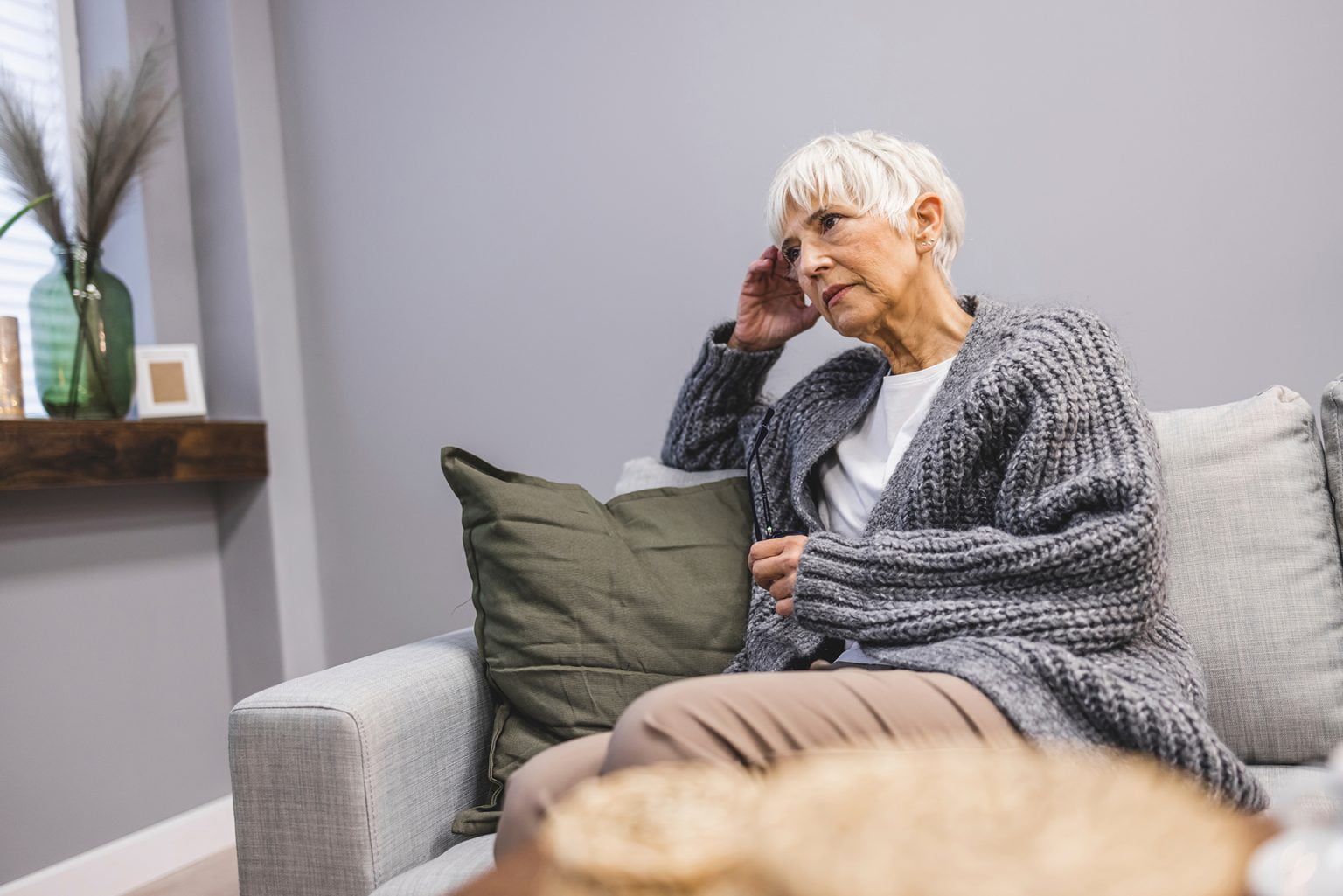 Upset mid-age woman sitting on sofa indoors