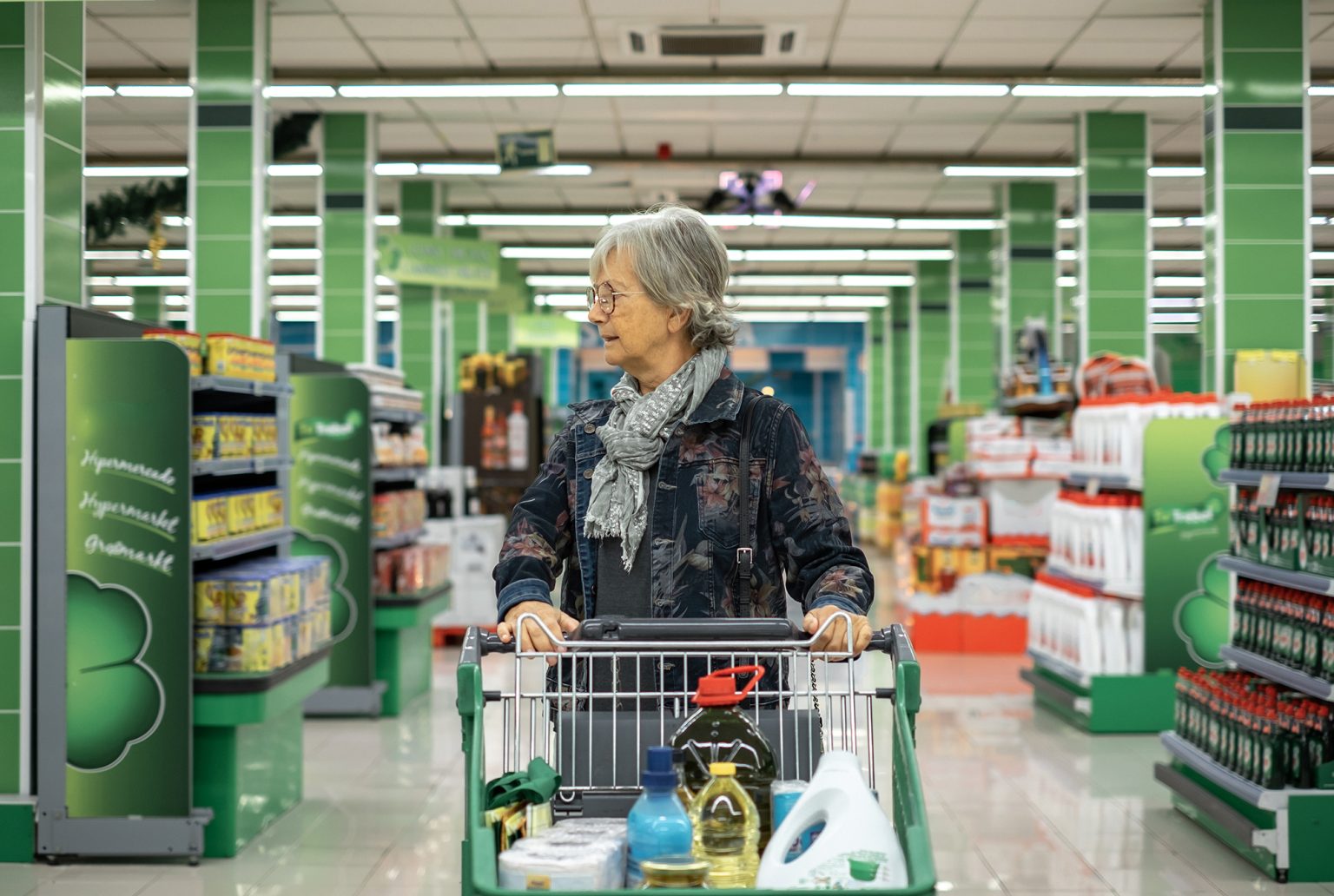 senior woman pushing cart in supermarket looking at the products on display