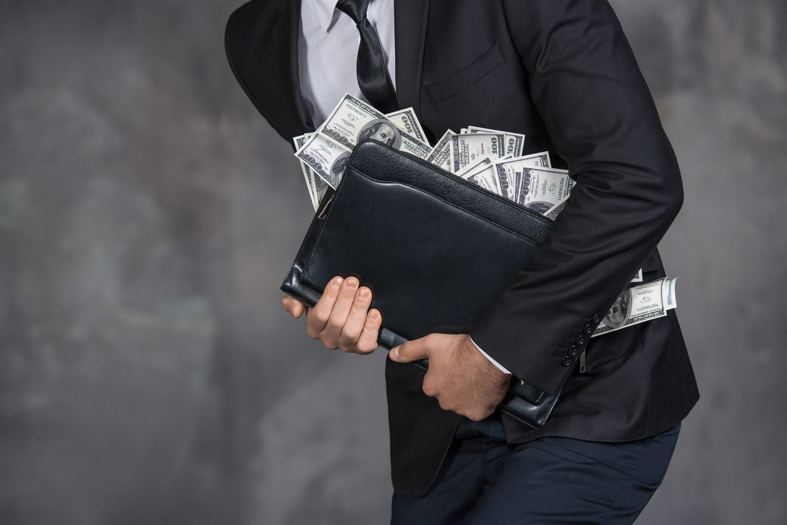 Businessman holding portfolio with lots of money falling out