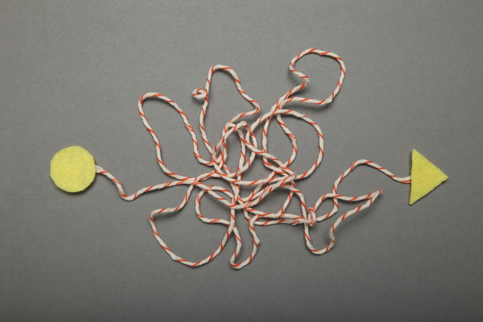 Tangled string with a circle on one side and an arrow on the other