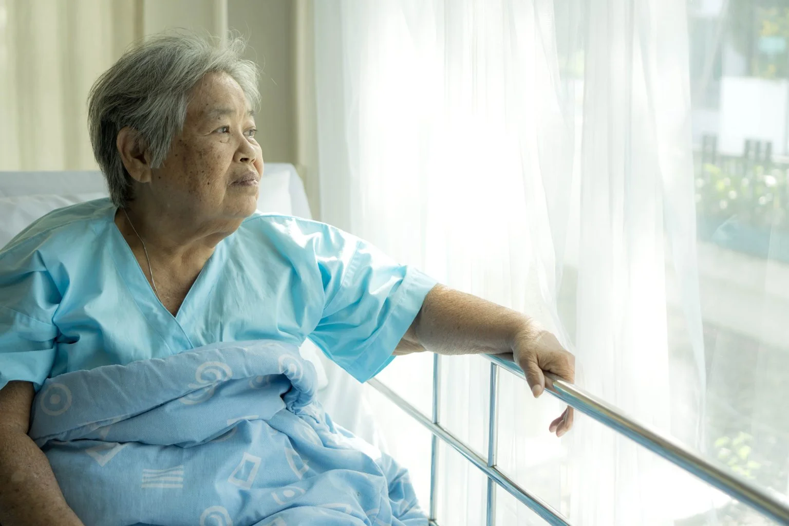 Elderly patient in hospital bed looking out the window