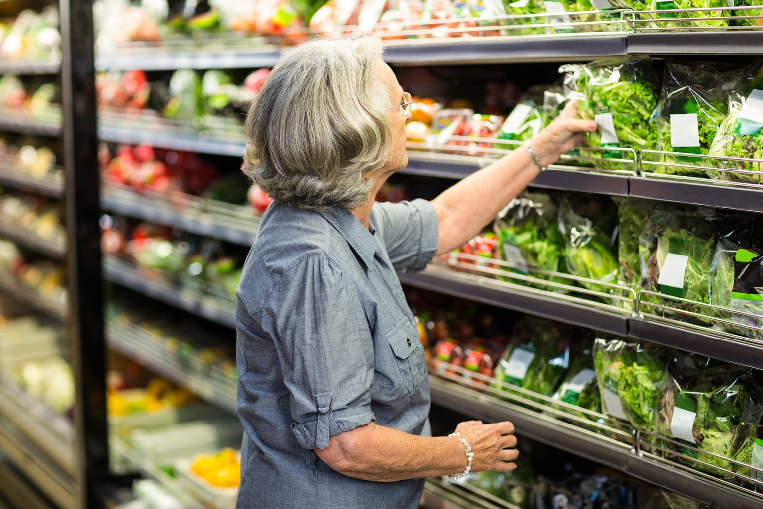 Senior woman picking out vegetables at a grocery store