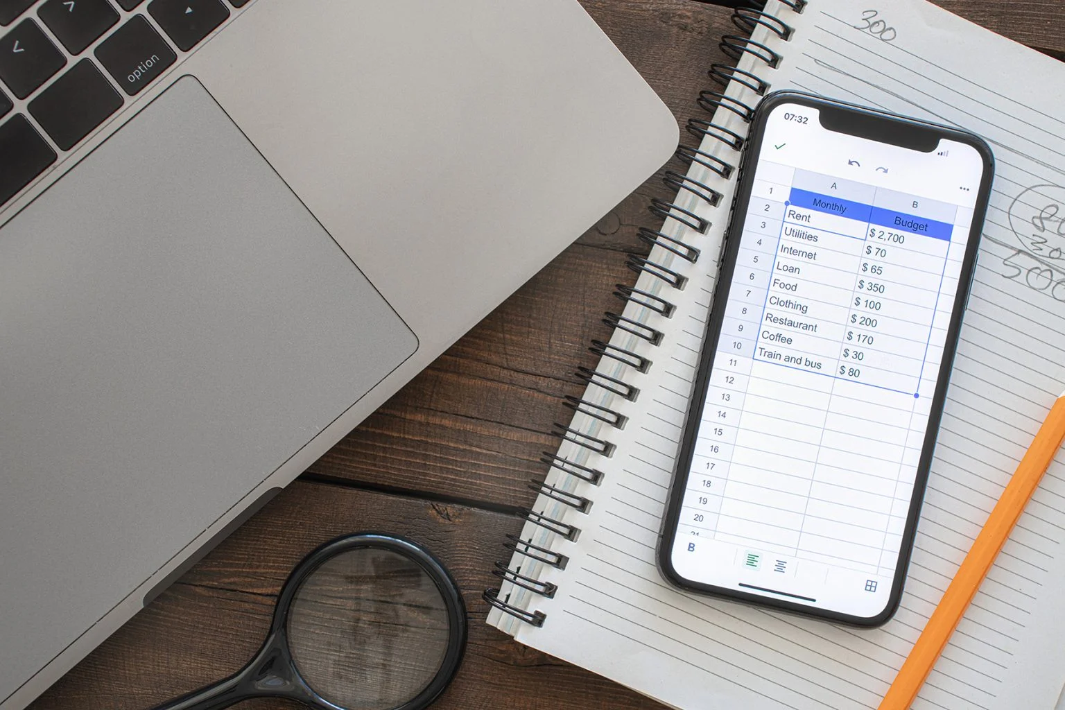 Smartphone with monthly budget list on wooden table