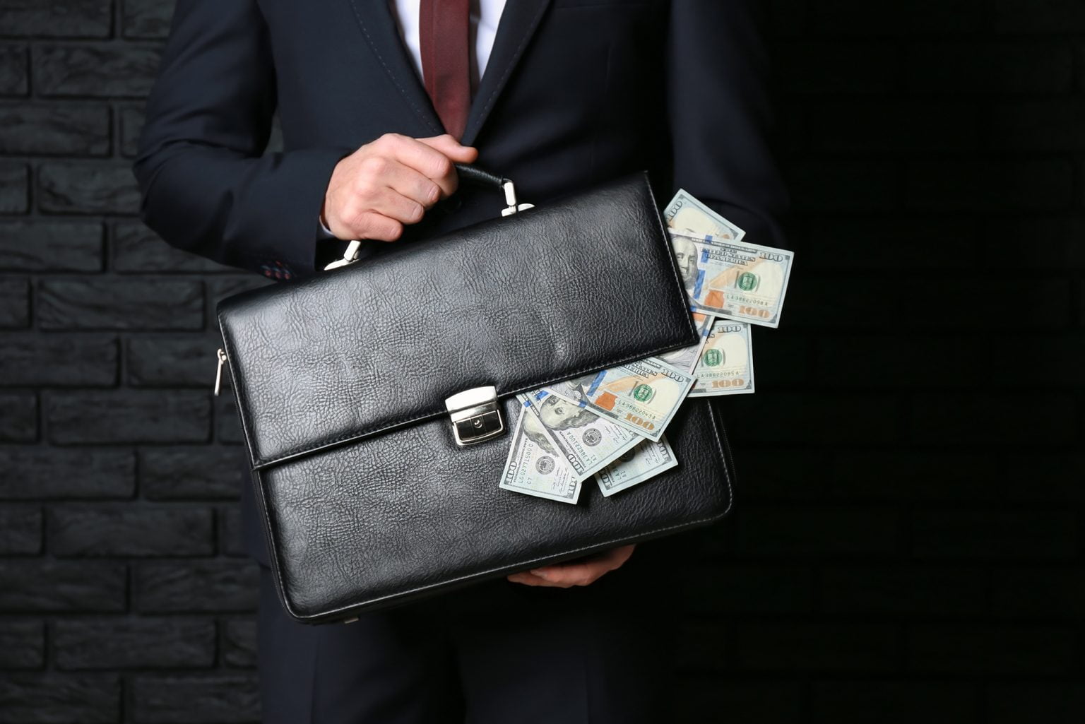Businessman holding briefcase with dollar bills falling ou