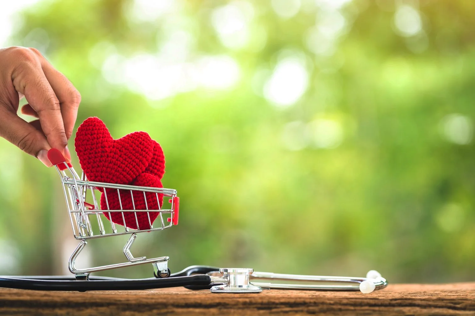 Man pushing a shopping cart and the heart put on inside and stethoscope with showing put on the wood in the public park