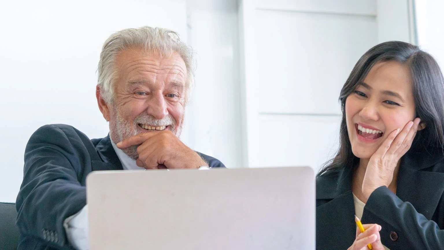 Senior businessman and young businesswoman partner are happy and talking and working on around desk office