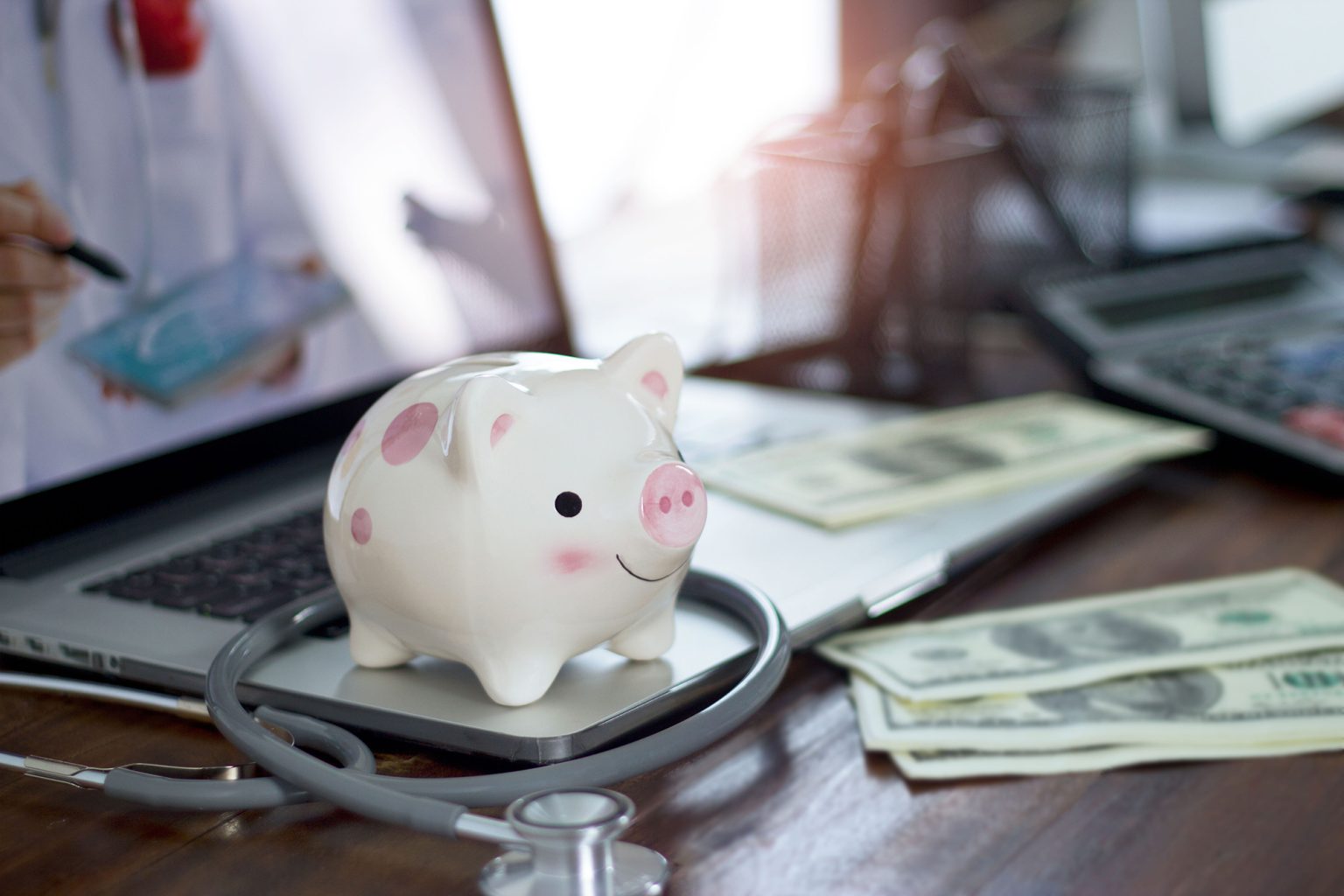 Piggy bank and stethoscope on computer laptop