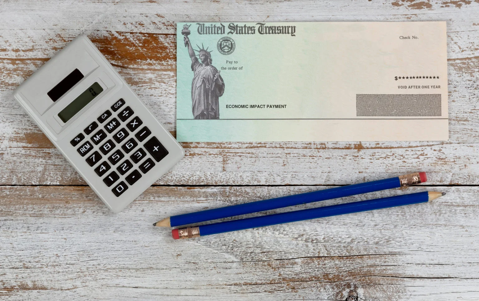 Economic impact stimulus check on desktop with pencils and calcu