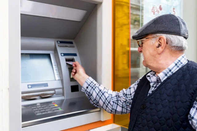elderly man inserting credit card to ATM