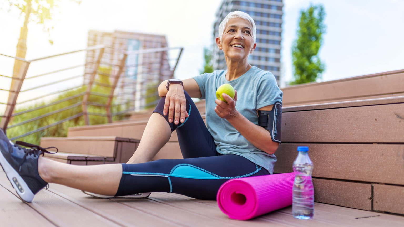 Smiling woman eating green apple.